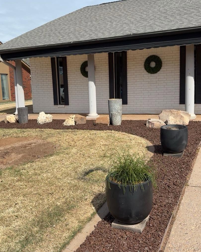 A newly refreshed front landscape with dark mulch and decorative stone